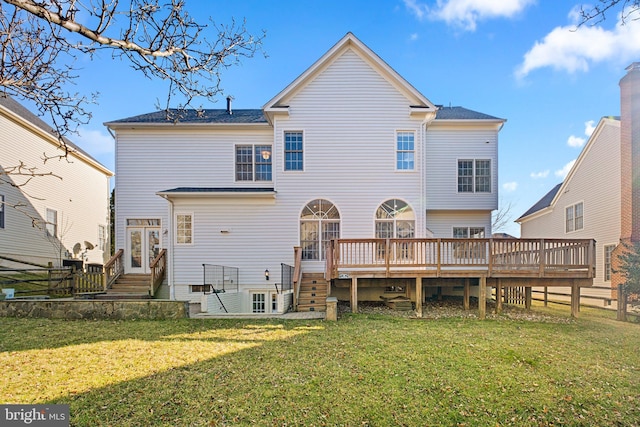 back of property with entry steps, fence, a deck, and a lawn