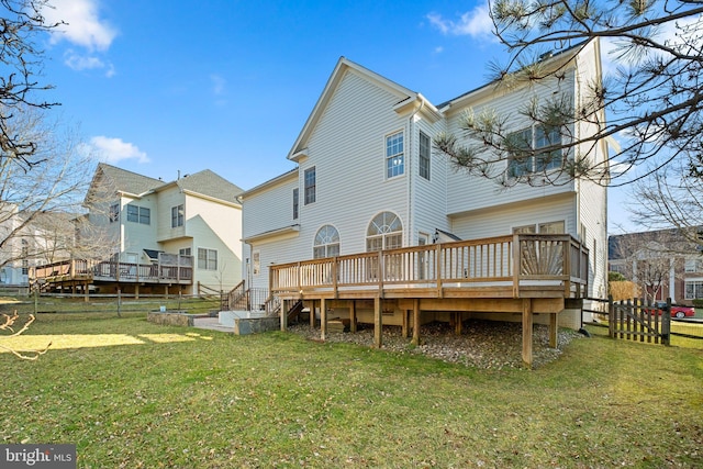 back of house featuring a lawn, a wooden deck, and fence