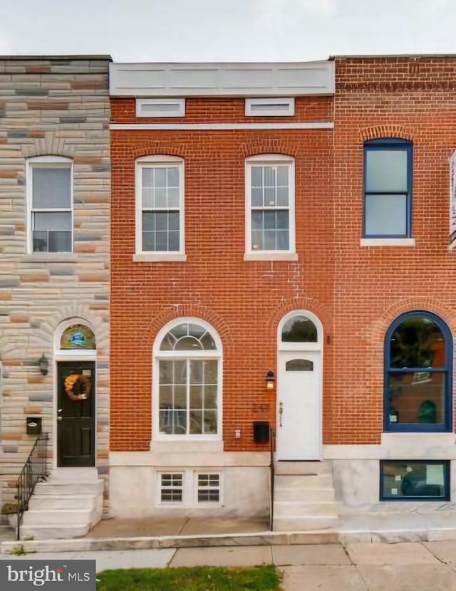 view of property with entry steps, stone siding, and brick siding