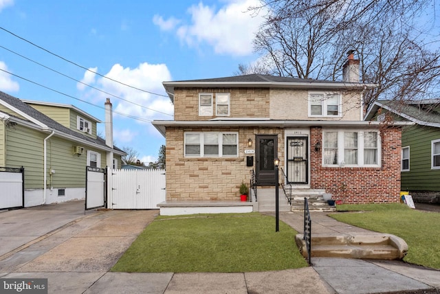 american foursquare style home with stone siding, a gate, a chimney, and a front yard