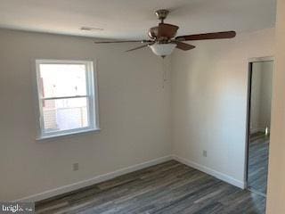 spare room with baseboards and wood finished floors