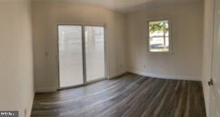 spare room with dark wood-type flooring and baseboards