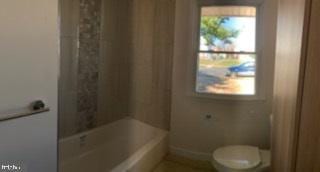 full bathroom with baseboards, toilet, and shower / tub combo with curtain