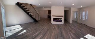 unfurnished living room with recessed lighting, stairway, wood finished floors, and a fireplace