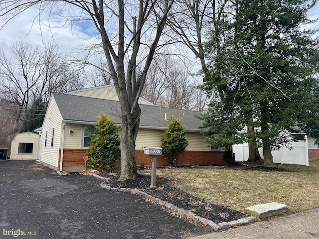 view of side of property featuring aphalt driveway and roof with shingles