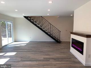 unfurnished living room with stairs, recessed lighting, and wood finished floors