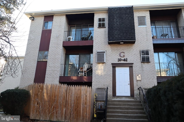 exterior space featuring brick siding, a shingled roof, and fence