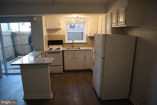 kitchen with dark wood finished floors, a peninsula, white cabinets, white appliances, and a sink