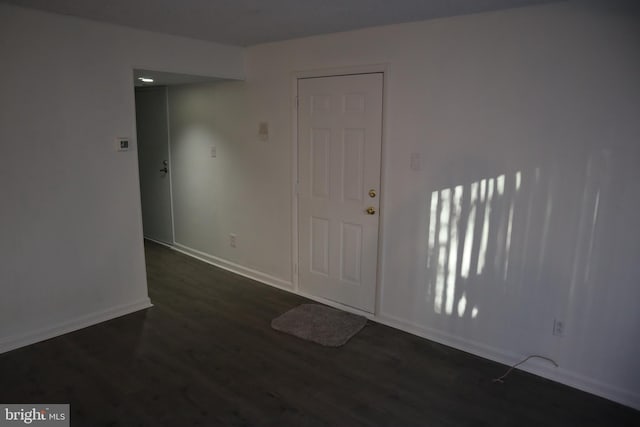 unfurnished room with baseboards and dark wood-style floors