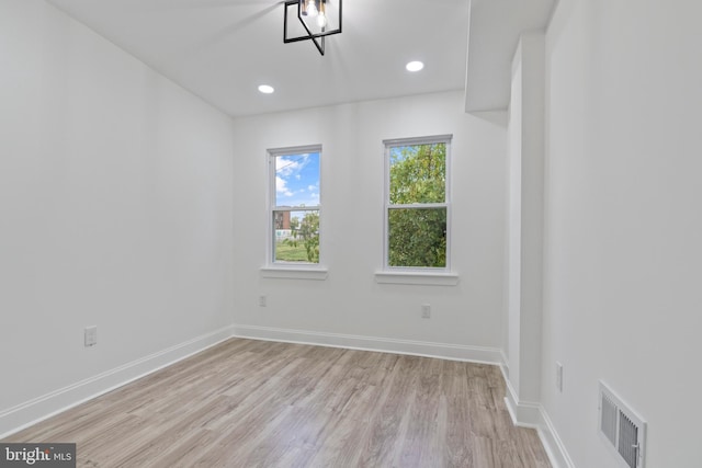 spare room featuring light wood finished floors, baseboards, and visible vents