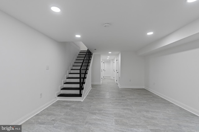 finished below grade area featuring stairs, baseboards, and recessed lighting