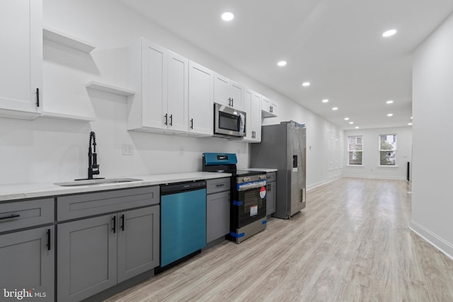 kitchen featuring appliances with stainless steel finishes, light wood-type flooring, white cabinetry, a sink, and recessed lighting