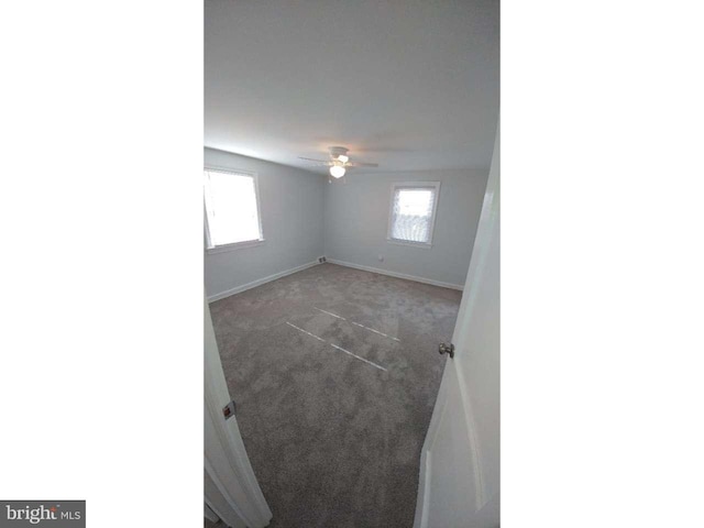 spare room featuring baseboards, carpet flooring, a ceiling fan, and a healthy amount of sunlight