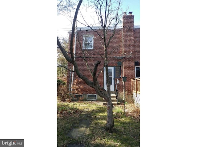 exterior space featuring brick siding and a chimney