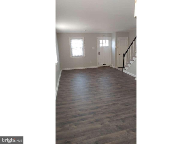 foyer with dark wood finished floors, stairway, and baseboards