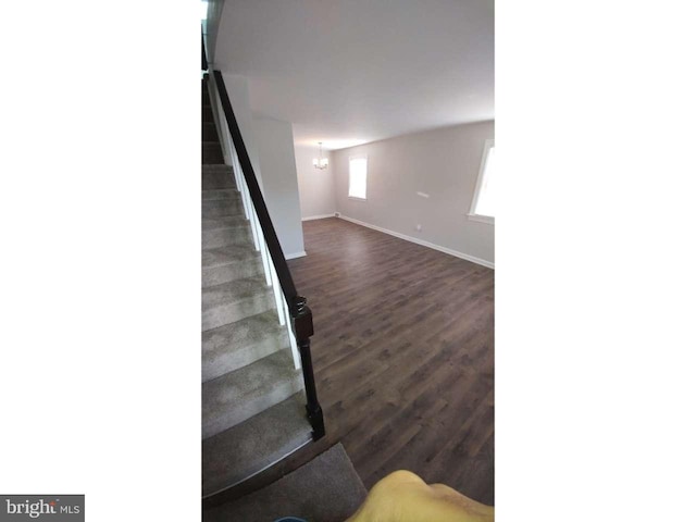 stairs featuring baseboards, a notable chandelier, and wood finished floors