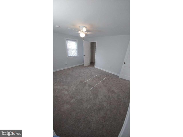 carpeted empty room with ceiling fan and baseboards