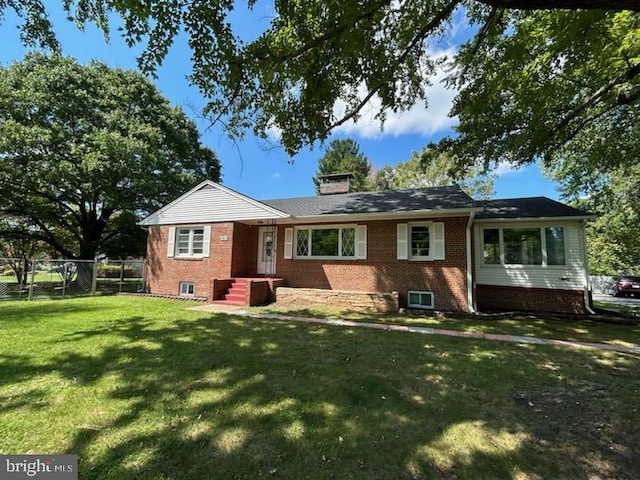 ranch-style home featuring brick siding, a chimney, a front yard, a gate, and fence