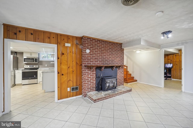 unfurnished living room with light tile patterned floors, stairs, wooden walls, and visible vents