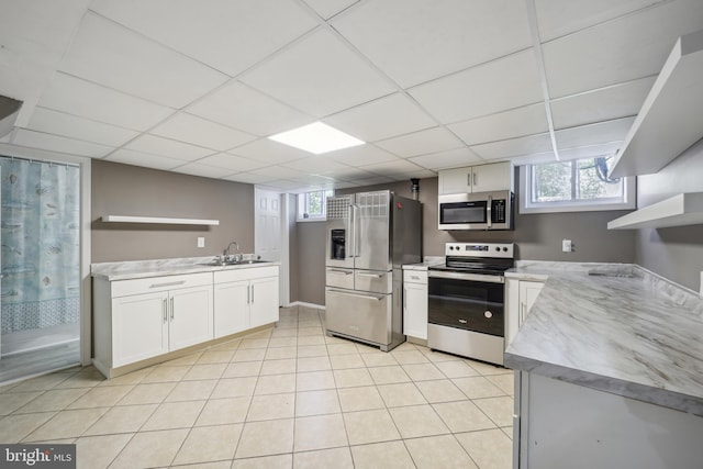 kitchen with light tile patterned floors, a sink, white cabinetry, appliances with stainless steel finishes, and open shelves