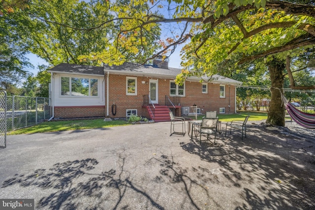 rear view of property with a patio area, a chimney, fence, and brick siding