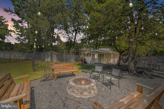 view of patio with a fenced backyard, a fire pit, and an outdoor structure