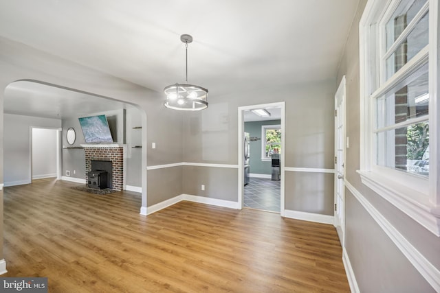 unfurnished dining area with light wood-style floors, baseboards, and arched walkways