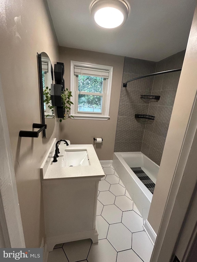 full bathroom with a tile shower, vanity, baseboards, and tile patterned floors