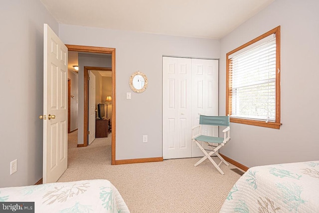 carpeted bedroom featuring baseboards and a closet