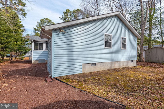 view of side of home with crawl space, a storage shed, and an outbuilding