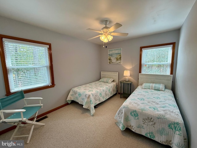 bedroom featuring carpet flooring, multiple windows, a ceiling fan, and baseboards