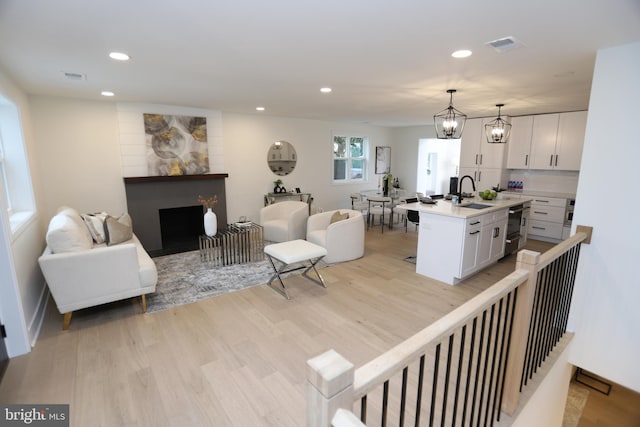 living room with recessed lighting, a fireplace, light wood-style flooring, and an inviting chandelier