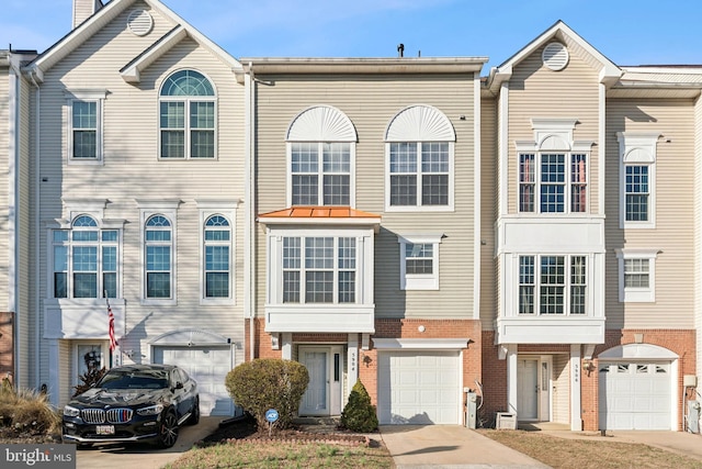 view of property featuring brick siding, driveway, and an attached garage