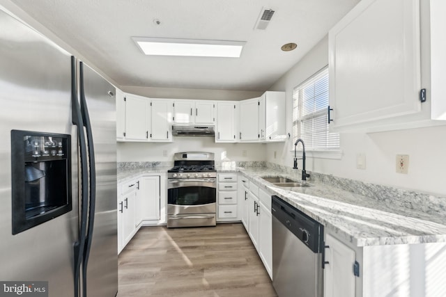 kitchen with visible vents, light wood finished floors, a sink, stainless steel appliances, and under cabinet range hood