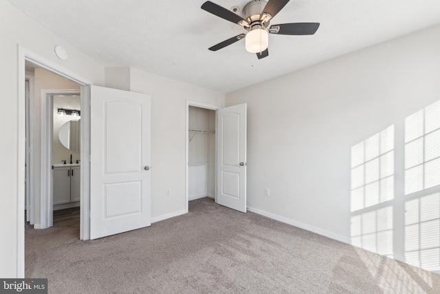 unfurnished bedroom with a sink, a closet, carpet flooring, baseboards, and ceiling fan