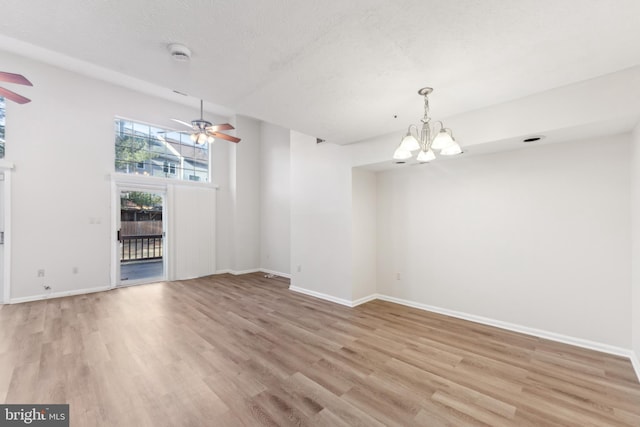 unfurnished dining area with light wood-type flooring, baseboards, a textured ceiling, and ceiling fan with notable chandelier