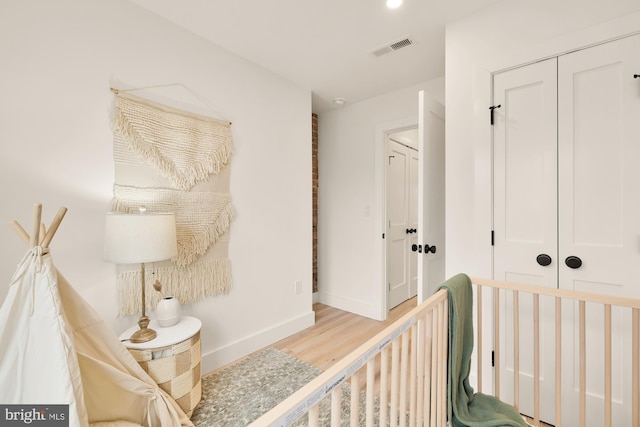 hallway with baseboards, visible vents, and wood finished floors