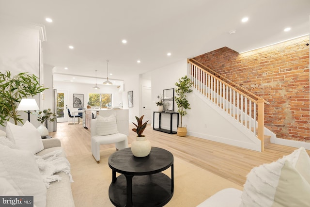 living area featuring recessed lighting, brick wall, baseboards, stairs, and light wood-type flooring