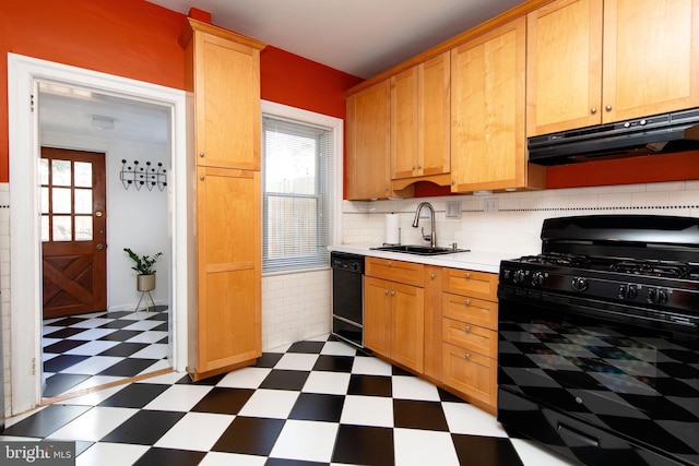 kitchen with black appliances, under cabinet range hood, a sink, and tile patterned floors