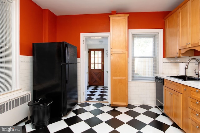 kitchen featuring a sink, light countertops, tile patterned floors, black appliances, and radiator