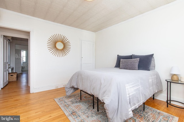 bedroom with crown molding, wood finished floors, and baseboards