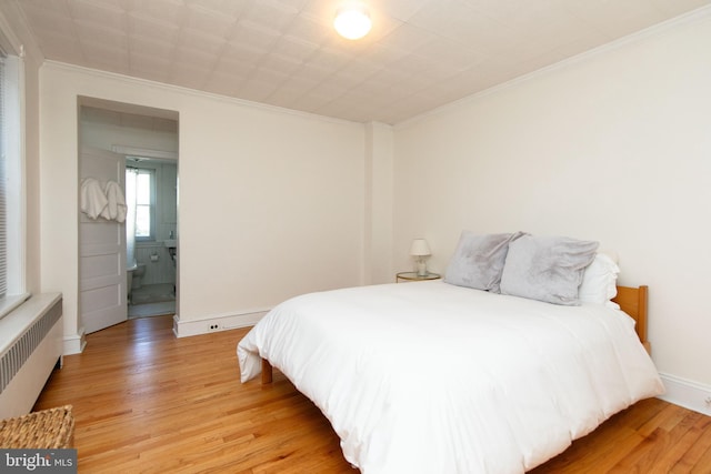 bedroom featuring baseboards, light wood finished floors, radiator heating unit, and crown molding