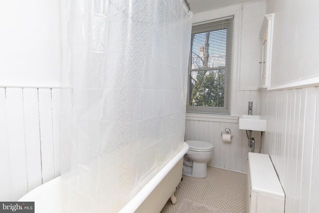 bathroom with toilet, a wainscoted wall, radiator heating unit, a shower with curtain, and tile patterned floors