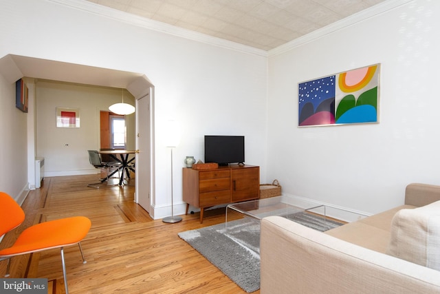 living area featuring baseboards, wood finished floors, and crown molding