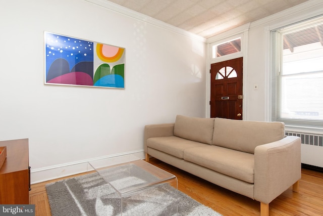 living area with baseboards, radiator heating unit, wood finished floors, and crown molding