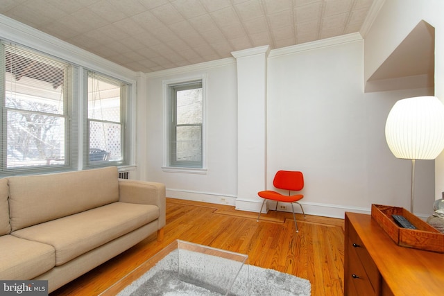 living room with ornamental molding, baseboards, and wood finished floors