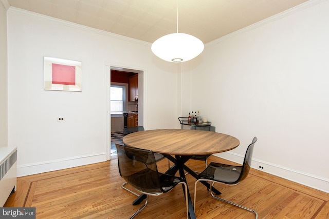 dining room featuring radiator, baseboards, ornamental molding, and wood finished floors