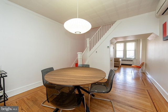 dining space featuring light wood finished floors, baseboards, a wall unit AC, radiator heating unit, and stairs