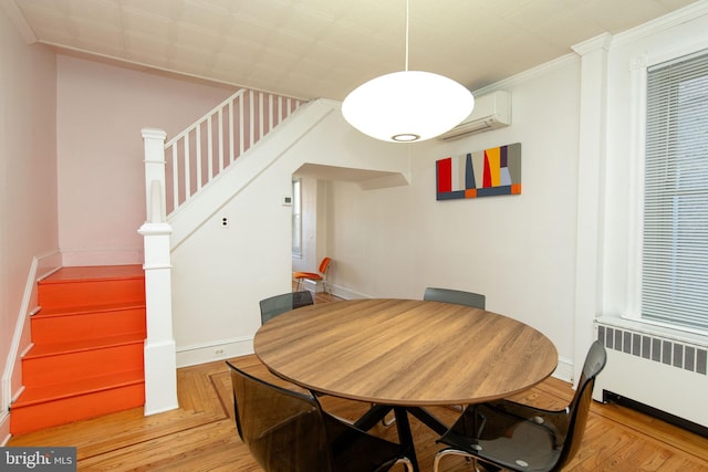 dining area featuring a wall unit AC, light wood-type flooring, radiator heating unit, and stairs