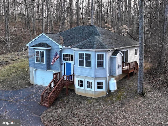 view of front of house with a shingled roof, an attached garage, and aphalt driveway